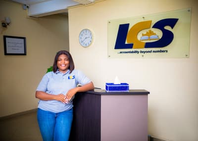 An LCS team member at the reception desk, beneath the LCS sign