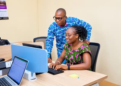 An LCS colleague guiding a team member through a spreadsheet on screen