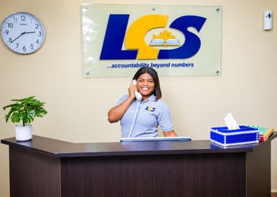 An LCS receptionist smiling as she answers the phone at the front desk, beneath the LCS sign
