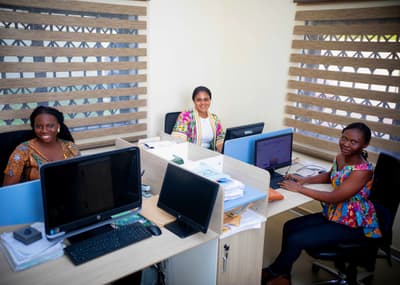 Three LCS team members smiling at their desks in the office